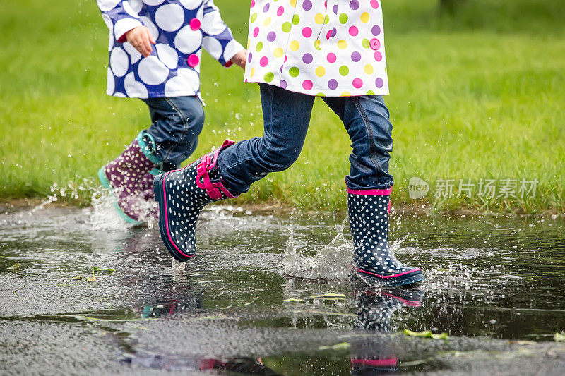 两个女孩在雨中穿过水坑