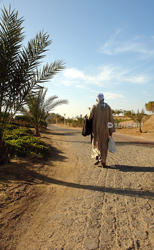 一名阿拉伯人在埃及沙漠附近的一条小路上行走