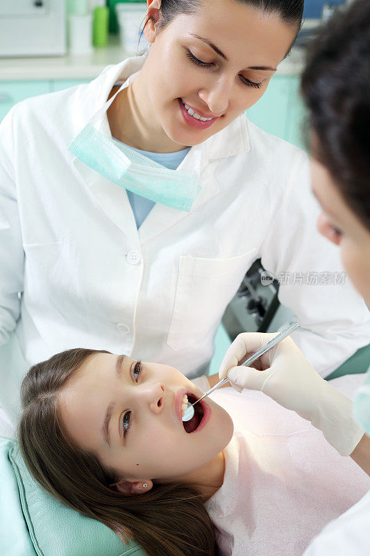 牙医正在检查一个女孩的牙齿。