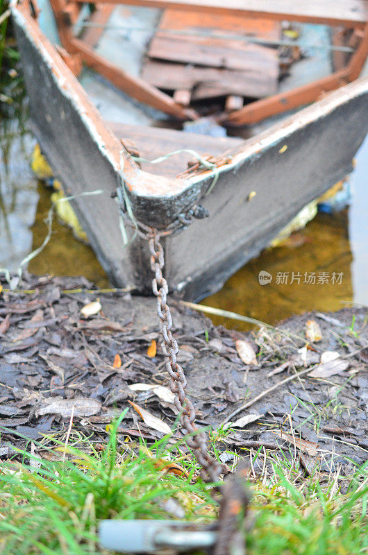 一条破船被一条铁链拴在河岸上。