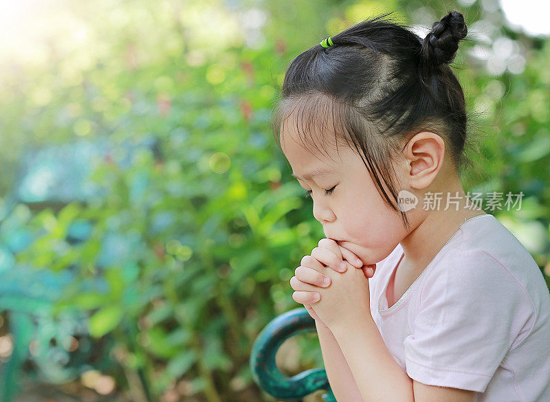 小女孩在花园里祈祷。