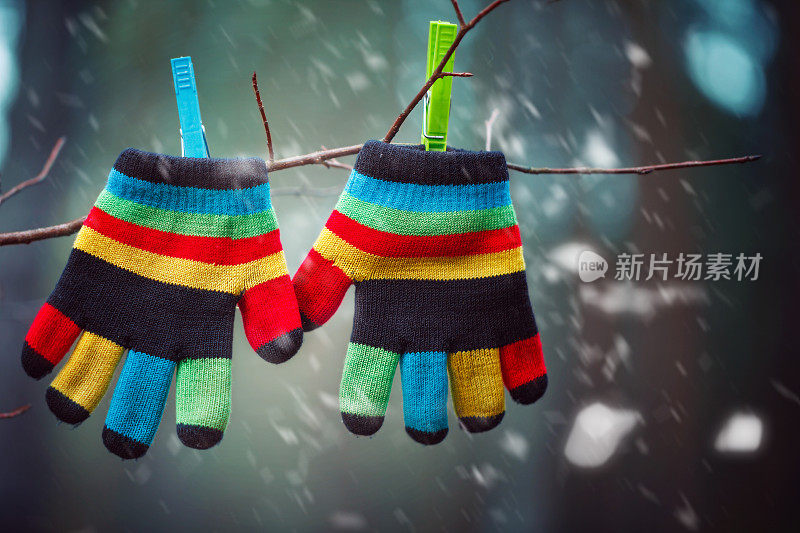 小婴儿连指手套，手套挂在下雪的冬天。