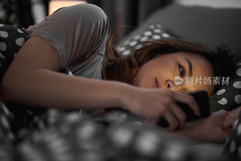 女孩躺在床上玩手机