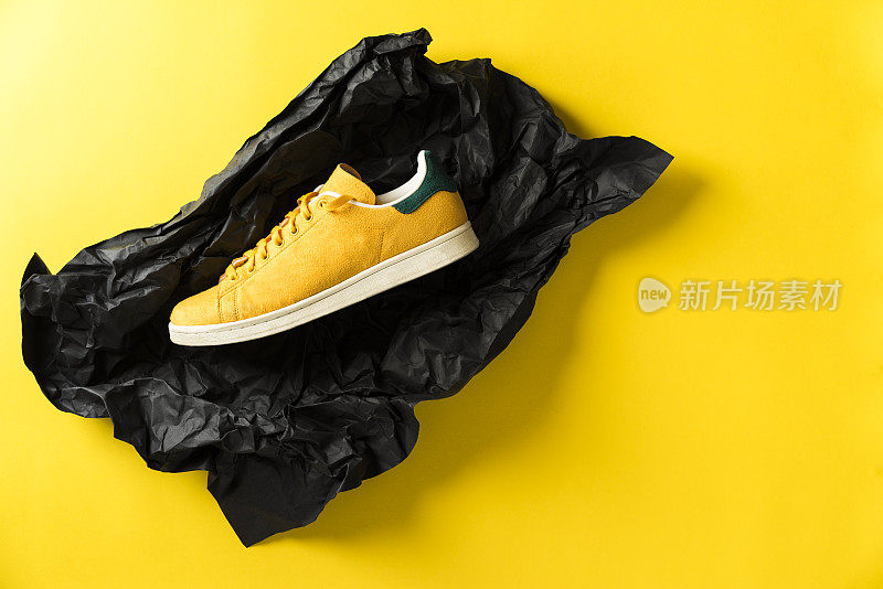 黄色运动鞋在黄色背景黑色包装纸