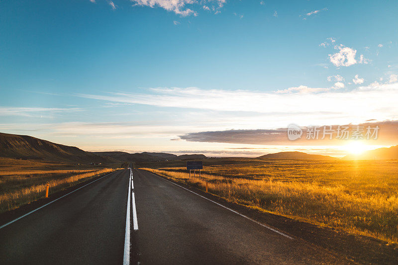 驾驶冰岛环城公路自驾游。冰岛1号公路，公路附近的风景全景图。旅游景点及露营路线。美丽的金色夕阳照亮了柏油路。