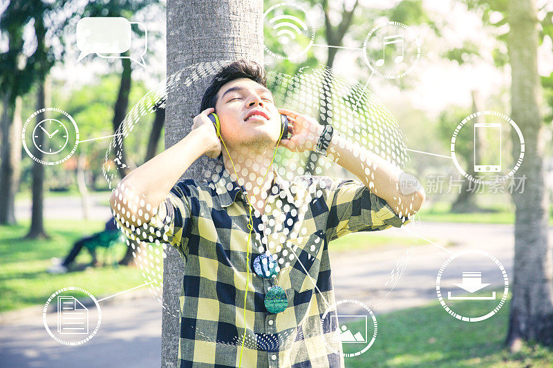 物联网概念，一个年轻人正在听着音乐，手持耳机连接互联网云网络，技术背景。
