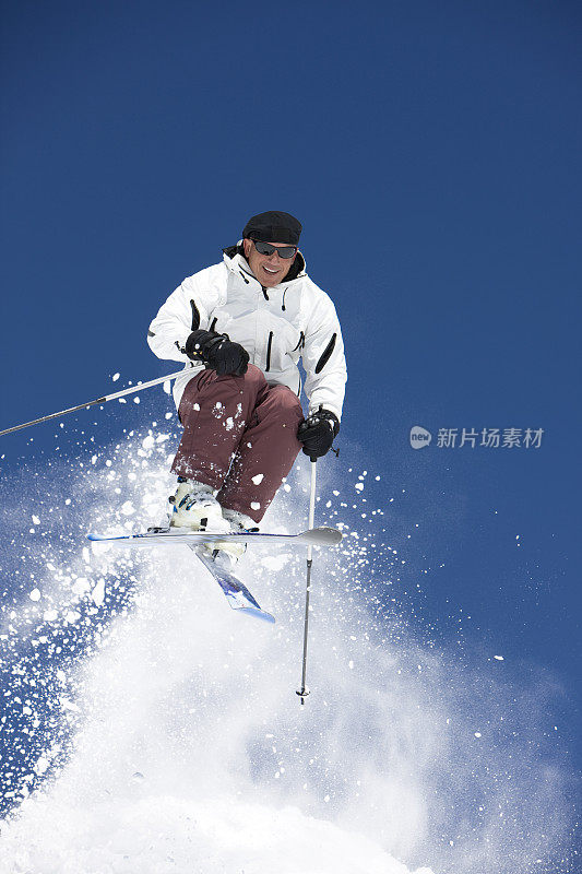 男滑雪者在明亮的蓝天下跳跃