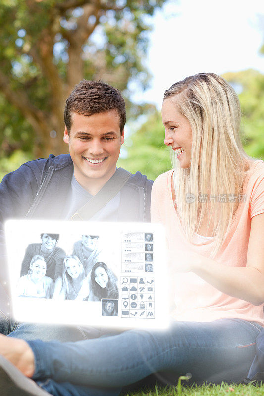 微笑的年轻夫妇在数字界面上看照片