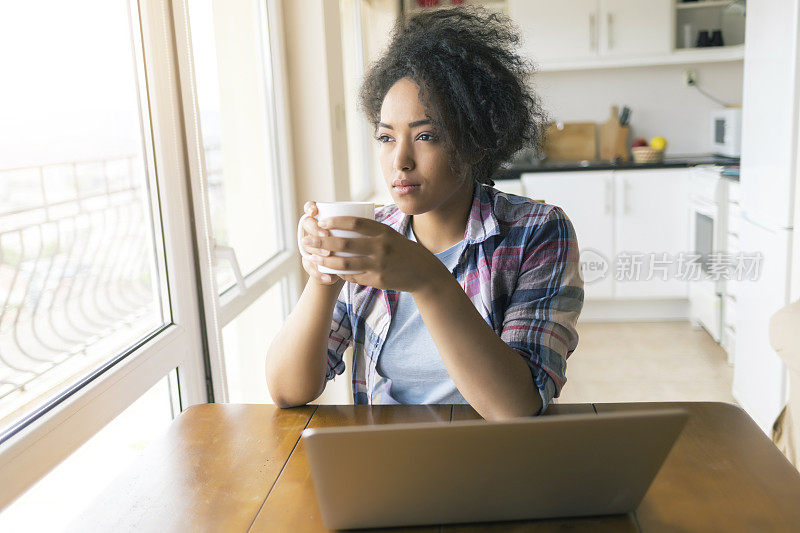 喝咖啡，在家里用笔记本电脑的女人