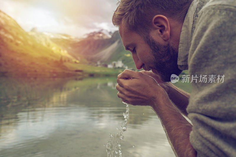 年轻人喝着山上湖泊的淡水