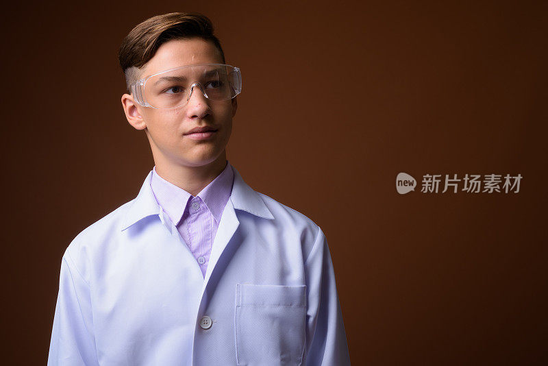 工作室拍摄的年轻英俊的医生戴着保护眼镜，反对彩色背景