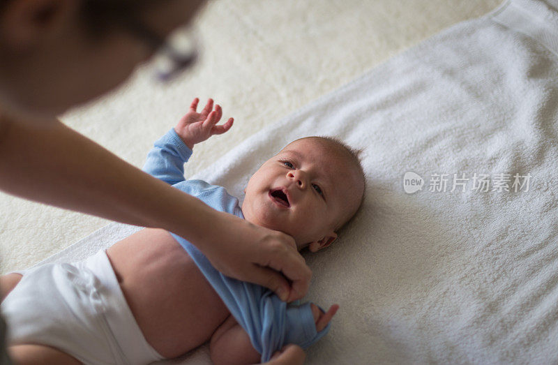 妈妈在给男婴换紧身衣