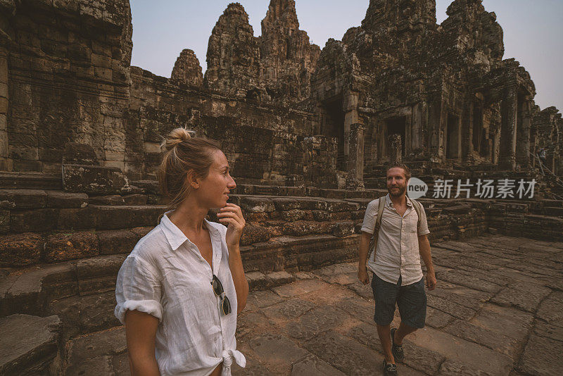 一对在亚洲旅游的游客，在夕阳下凝视美丽的古庙和古老的废墟;人发现探索理念