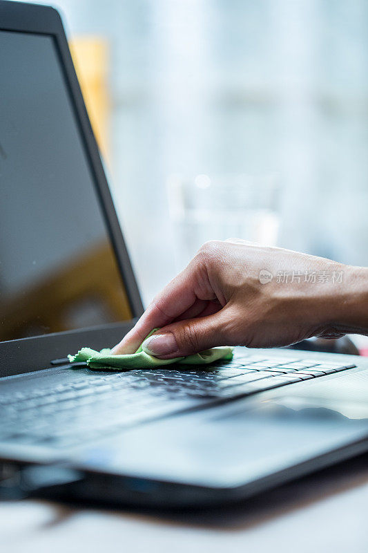 女人用抹布清洁电脑键盘