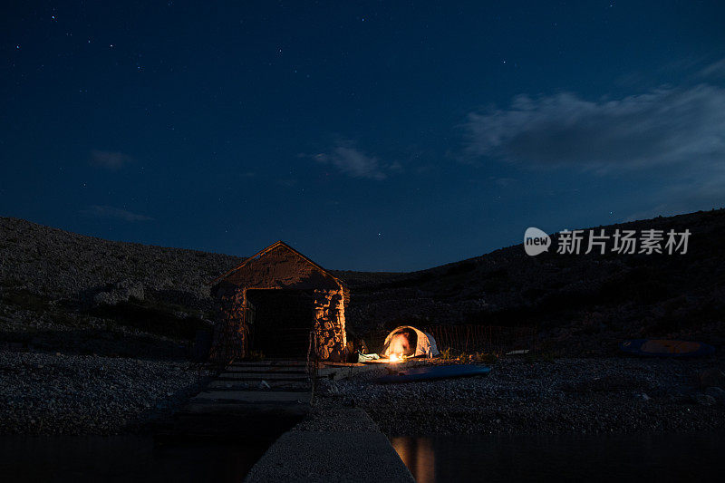 晚上在海边的一个旧小屋旁露营