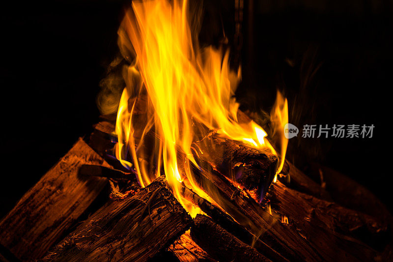 在冬天的夜晚，室外燃烧着的木头燃烧着温暖的橙色火焰