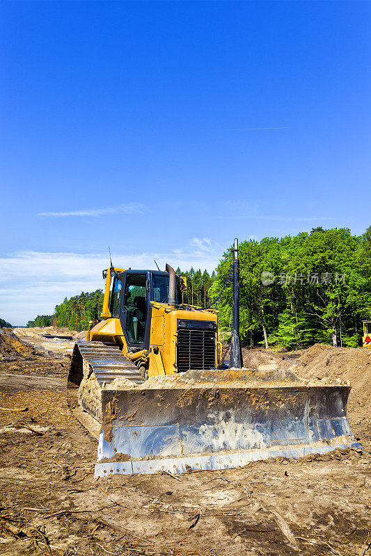 黄色的推土机正在为修筑公路铺路