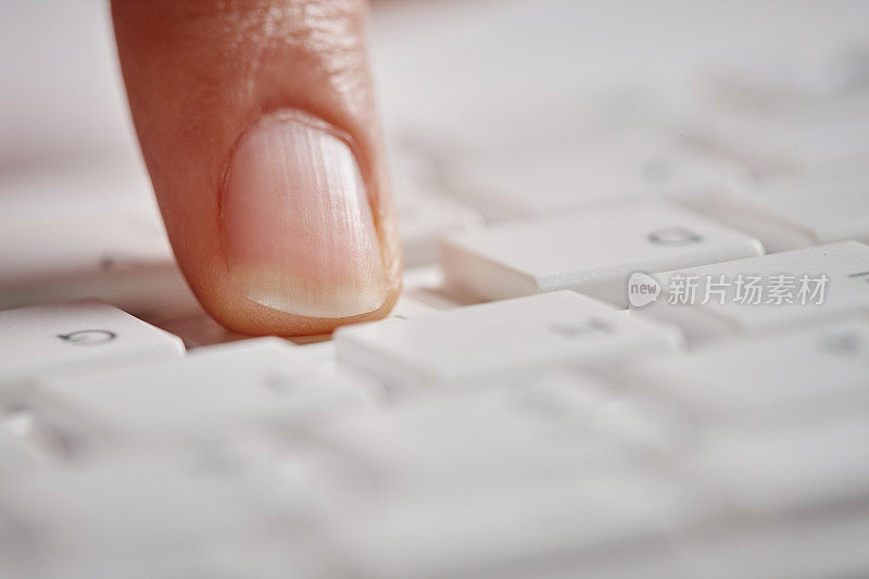 一位女性的手指敲击着白色的电脑键盘