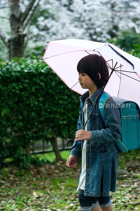 小女孩在雨中回家的侧视图