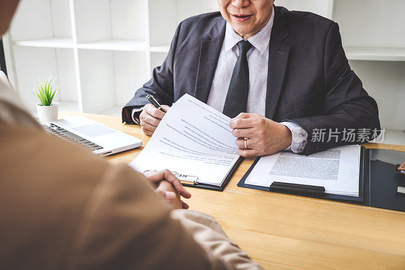 面试官或董事会在面试中阅读一份简历，雇主在面试一位年轻的女性求职者谈论现代办公室，就业和招聘理念