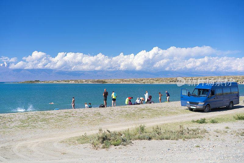 在吉尔吉斯斯坦的伊塞克库尔湖，游客在游完泳后穿着旅游货车