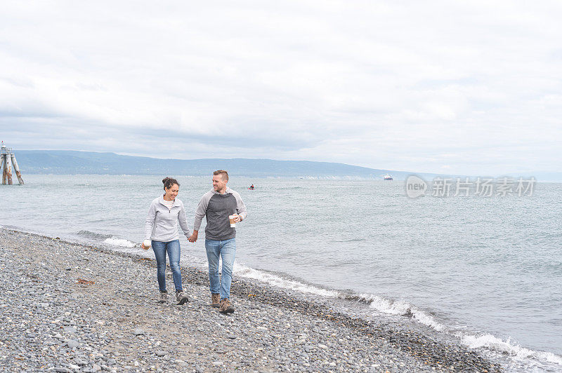 一对年轻的夫妇在一个多岩石的海湾散步