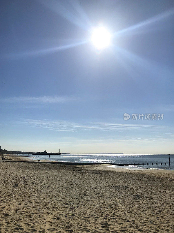 图片清晨的日出在英国海滩在夏天与波光粼粼的海面，木制的格罗讷侵蚀海防和码头在伯恩茅斯海滩海岸线，多塞特，英国，典型的海滨度假照片孤立的空沙滩