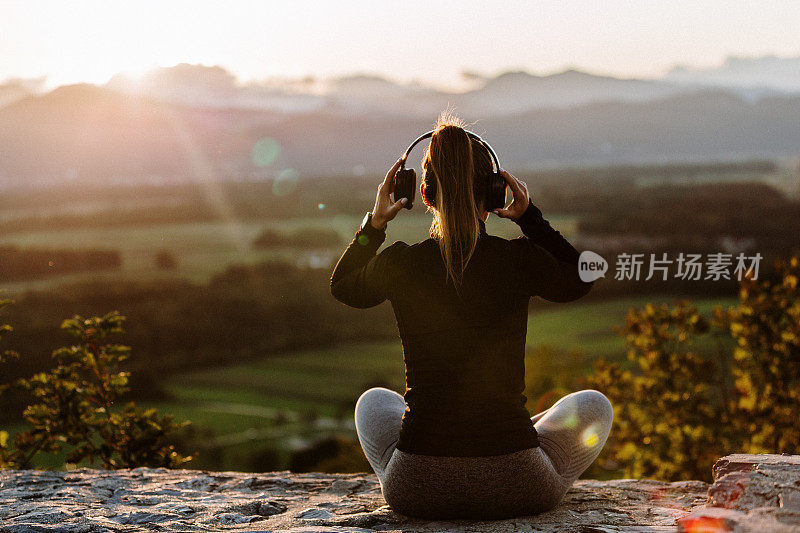 女孩戴着耳机在夕阳下听音乐