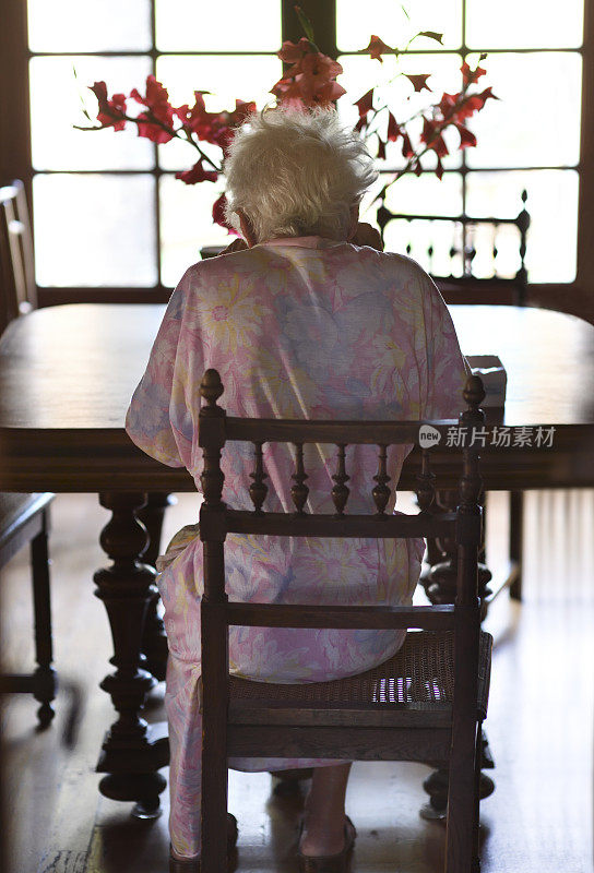 老妇人从后面坐在一张木桌前