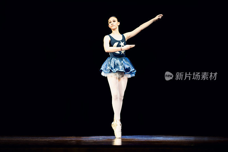 年轻女孩在黑暗的舞台上跳芭蕾舞