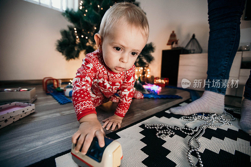 可爱的小孩在装饰好的房间里玩他的圣诞礼物