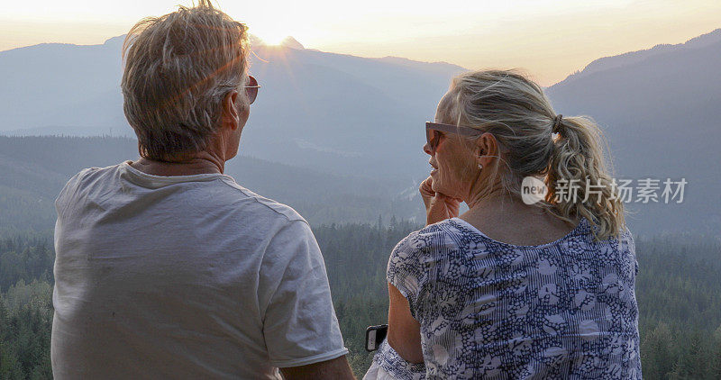 成熟的夫妇在山崖上放松，看外面的景色