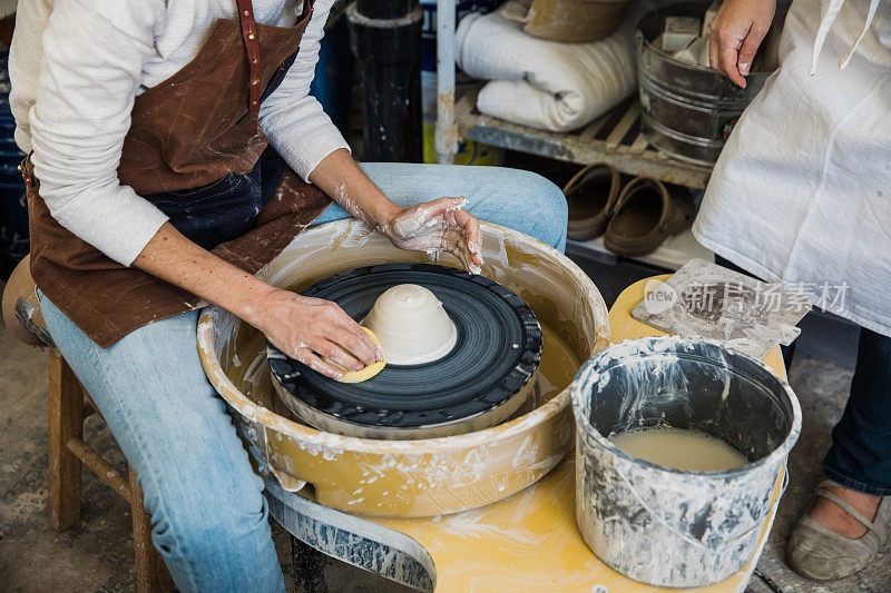 一个白人女艺术家准备在一个陶轮上塑造粘土
