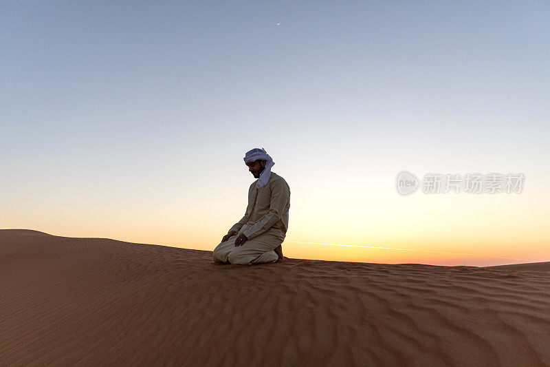 日落时分，沙漠中身着传统阿拉伯服饰的中东男子