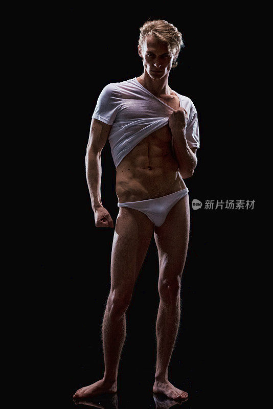 白人年轻男性脱衣舞娘前面的黑色背景穿着衬衫