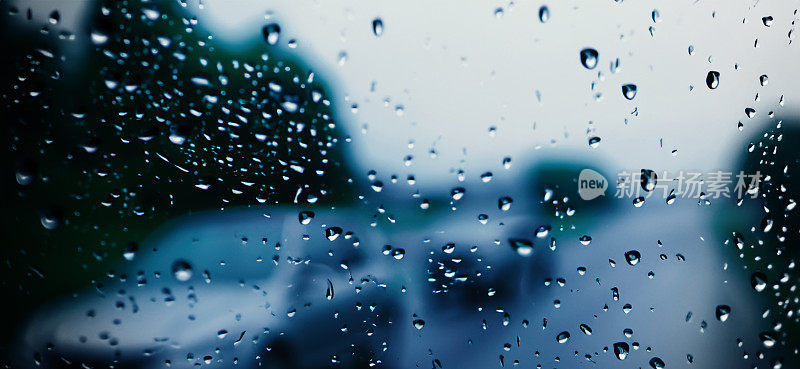 雨点落在汽车挡风玻璃或车窗上，背景是模糊的道路。雨季开车。雨滴落在汽车后视镜上。傍晚有雨的交通道路。毛毛雨会降低行车能见度