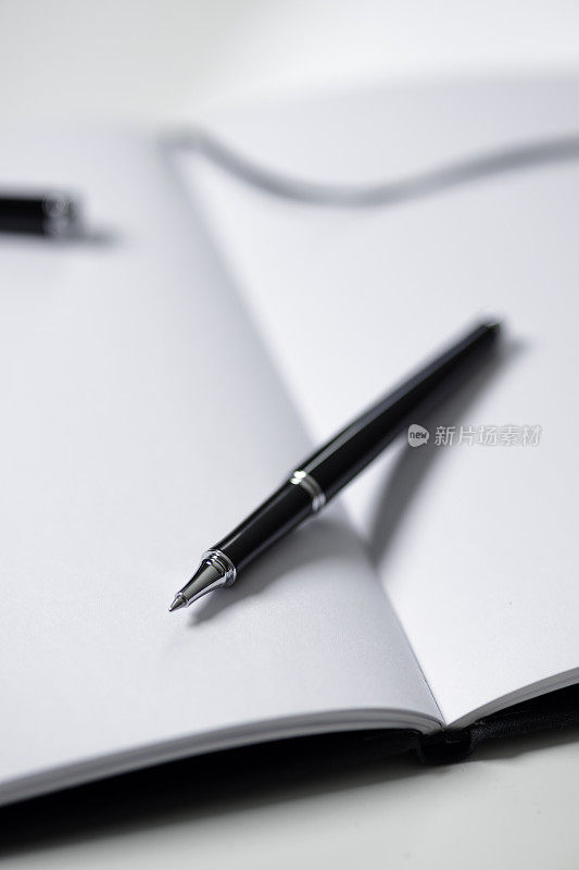 笔记本和黑色钢笔在桌子上