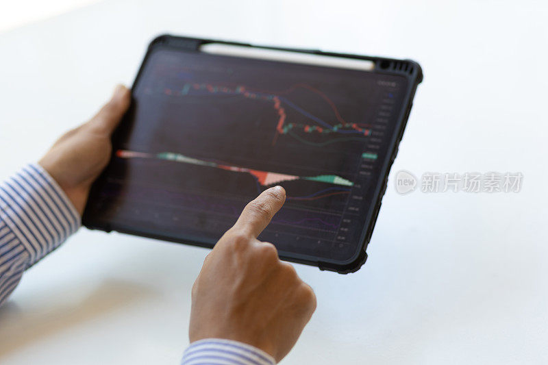 商人在平板电脑上分析股票市场投资图表。投资者在平板电脑上分析股市和外汇交易图表数据。