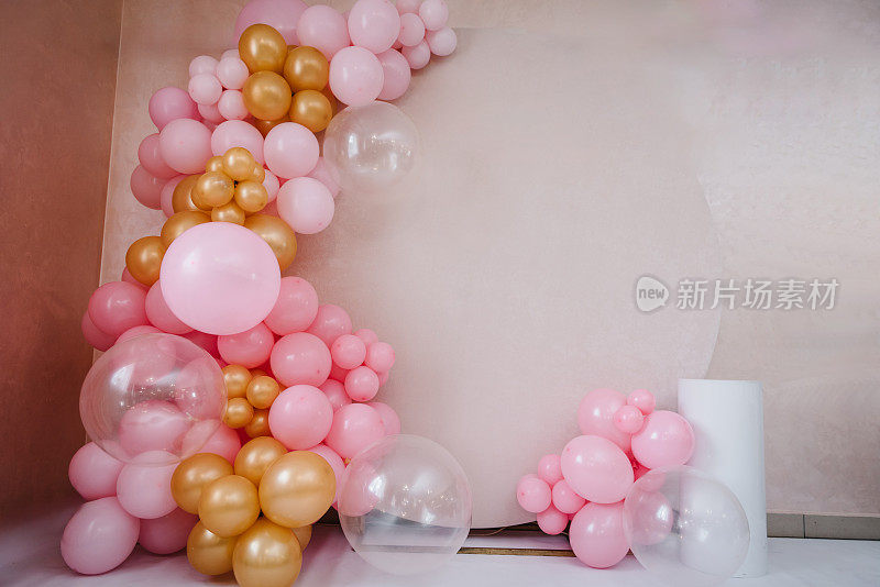 为聚会准备气球。米色照片墙装饰空间或地方用粉红色、金色的气球。时髦的春季装饰。庆祝活动的概念。生日聚会。婚宴上有摆蛋糕的桌子。
