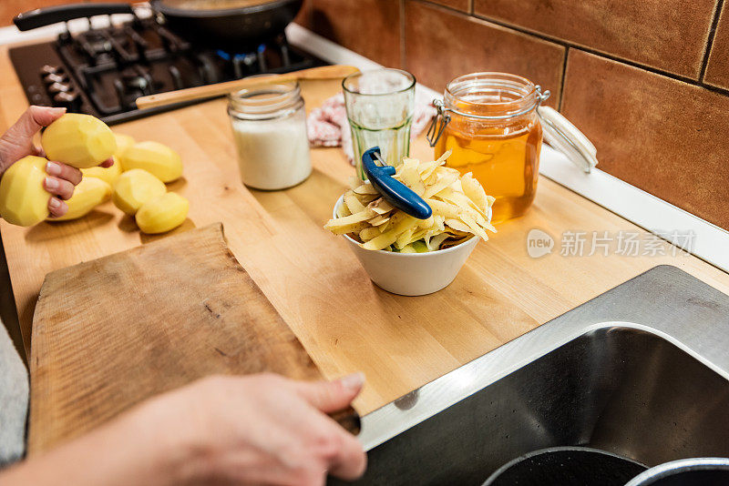 一名妇女在自家厨房为健康晚餐削土豆皮