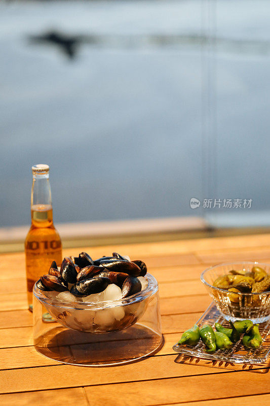 质朴的木桌上放着蒸贻贝和白葡萄酒