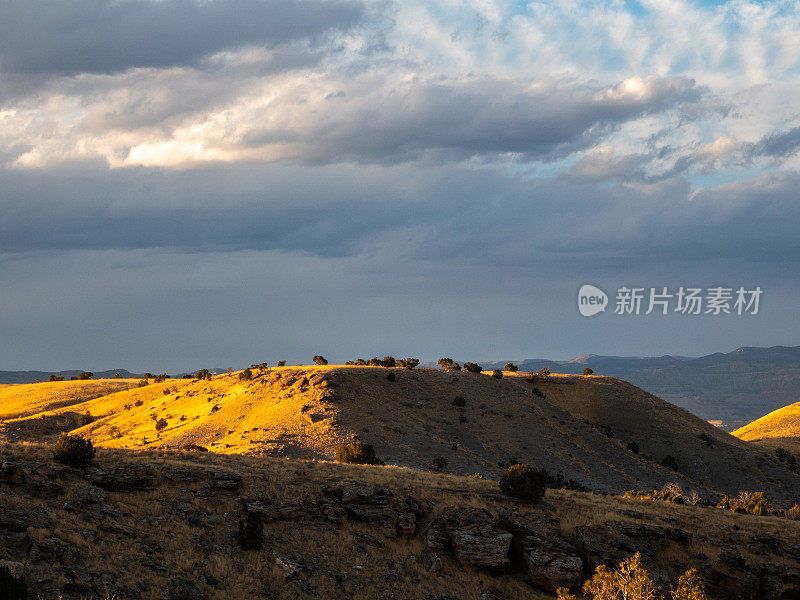 夕阳落在犹他州绿河沙漠的山丘上。