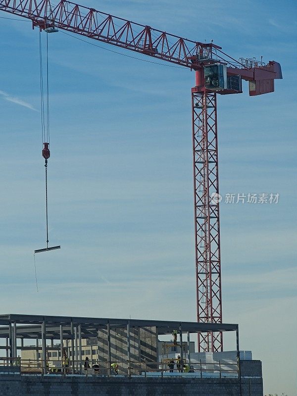 一架建筑起重机高高地飞过南卡罗来纳州的查尔斯顿市，将一根钢梁放置在新商业建筑的顶部