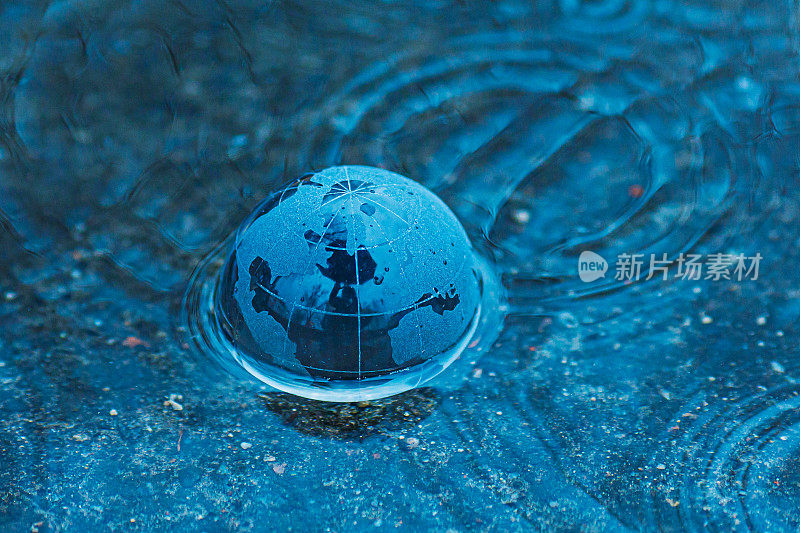 洪水。地球背景下的水。玻璃透明球。自然灾害。暴雨。水坑里的雨滴。