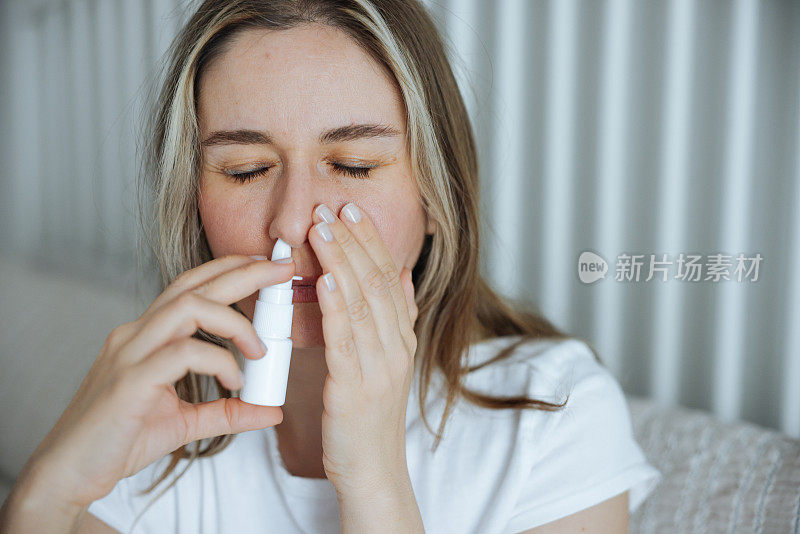 生病的年轻女子使用鼻腔喷雾剂