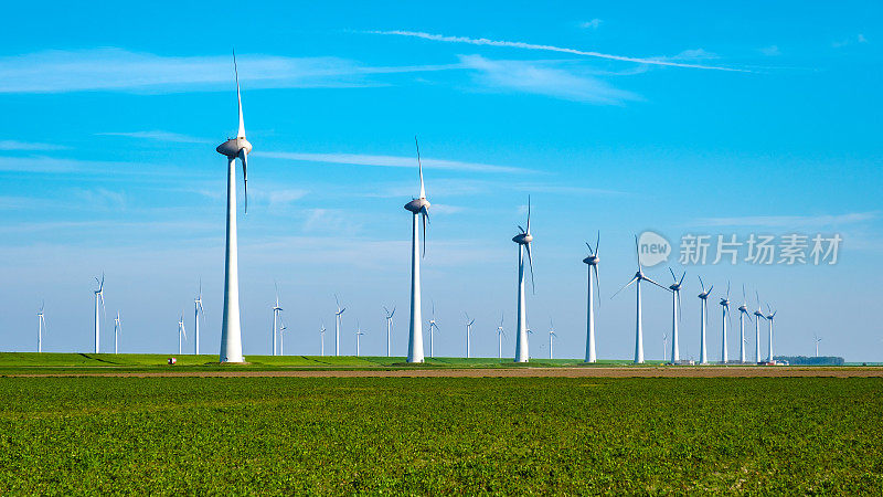 荷兰弗莱福兰，一片宁静的绿色田野上点缀着一排光滑的风车，它们的叶片在微风中优雅地转动