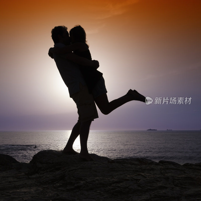 一对情侣在日落时接吻的剪影。