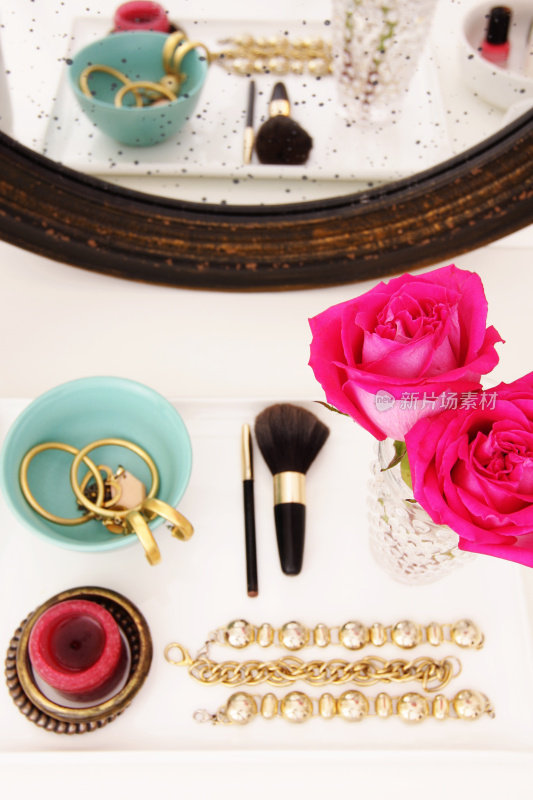 梳妆台与珠宝件和粉红玫瑰花瓶