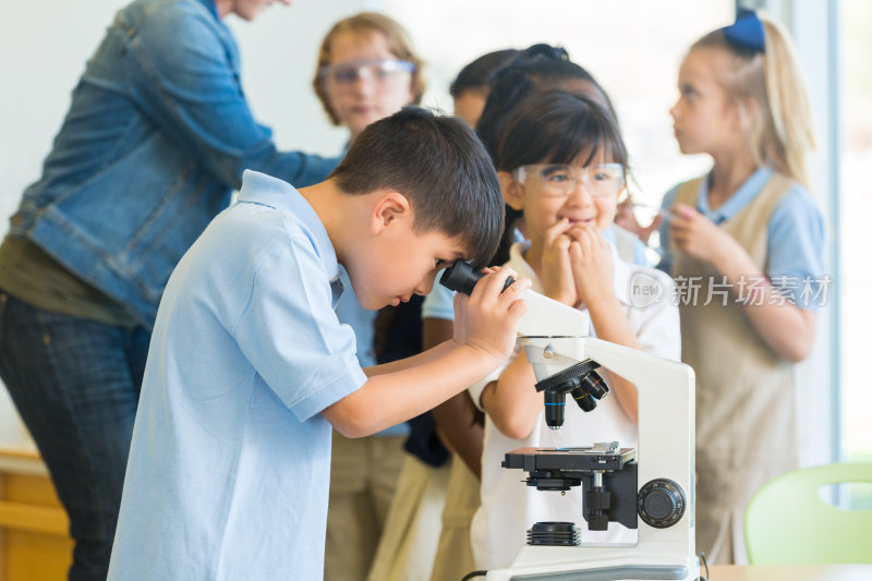 亚洲男孩是私立小学的学生，使用显微镜