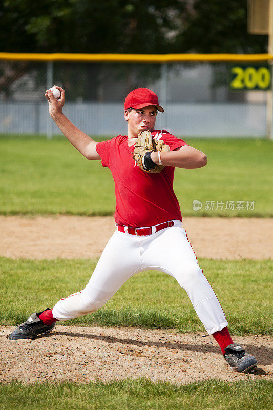 年轻的男棒球投手伸展在投手丘上
